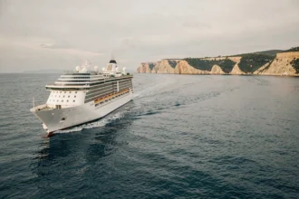 Paquebot de croisière naviguant sur une mer Méditerranée calme en octobre avec des falaises dorées en arrière-plan