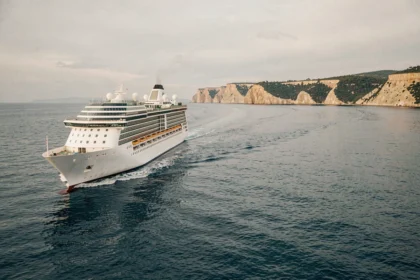 Paquebot de croisière naviguant sur une mer Méditerranée calme en octobre avec des falaises dorées en arrière-plan