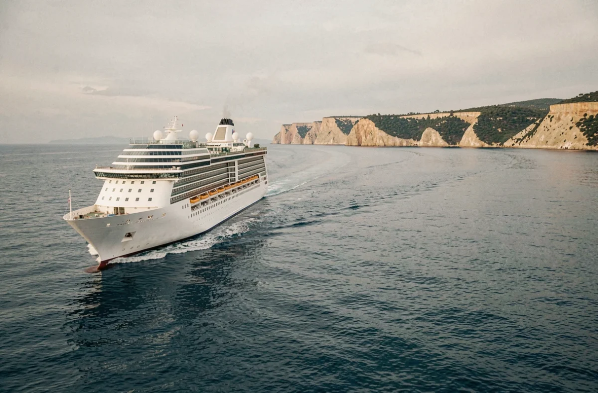 Paquebot de croisière naviguant sur une mer Méditerranée calme en octobre avec des falaises dorées en arrière-plan