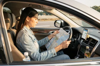 Femme consultant une carte routière et une application de navigation dans son SUV avant un long trajet ViaMichelin