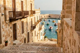 Village côtier traditionnel de Malte avec maisons en pierre dorée et bateaux colorés dans le port méditerranéen